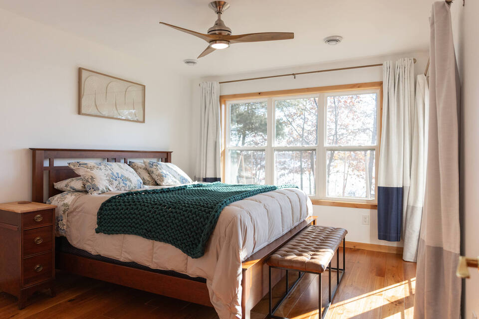 Cozy lakeside bedroom with wood floors and large windows by Ross Construction in Marathon, WI.