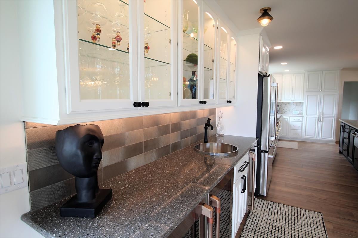 Built-in glass cabinetry and textured backsplash in a custom home bar by Ross Construction in Marathon, WI.