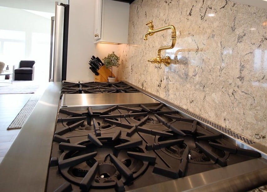 Close-up of Ross Construction custom kitchen stove with marble backsplash and pot filler in Rib Mountain, WI.
