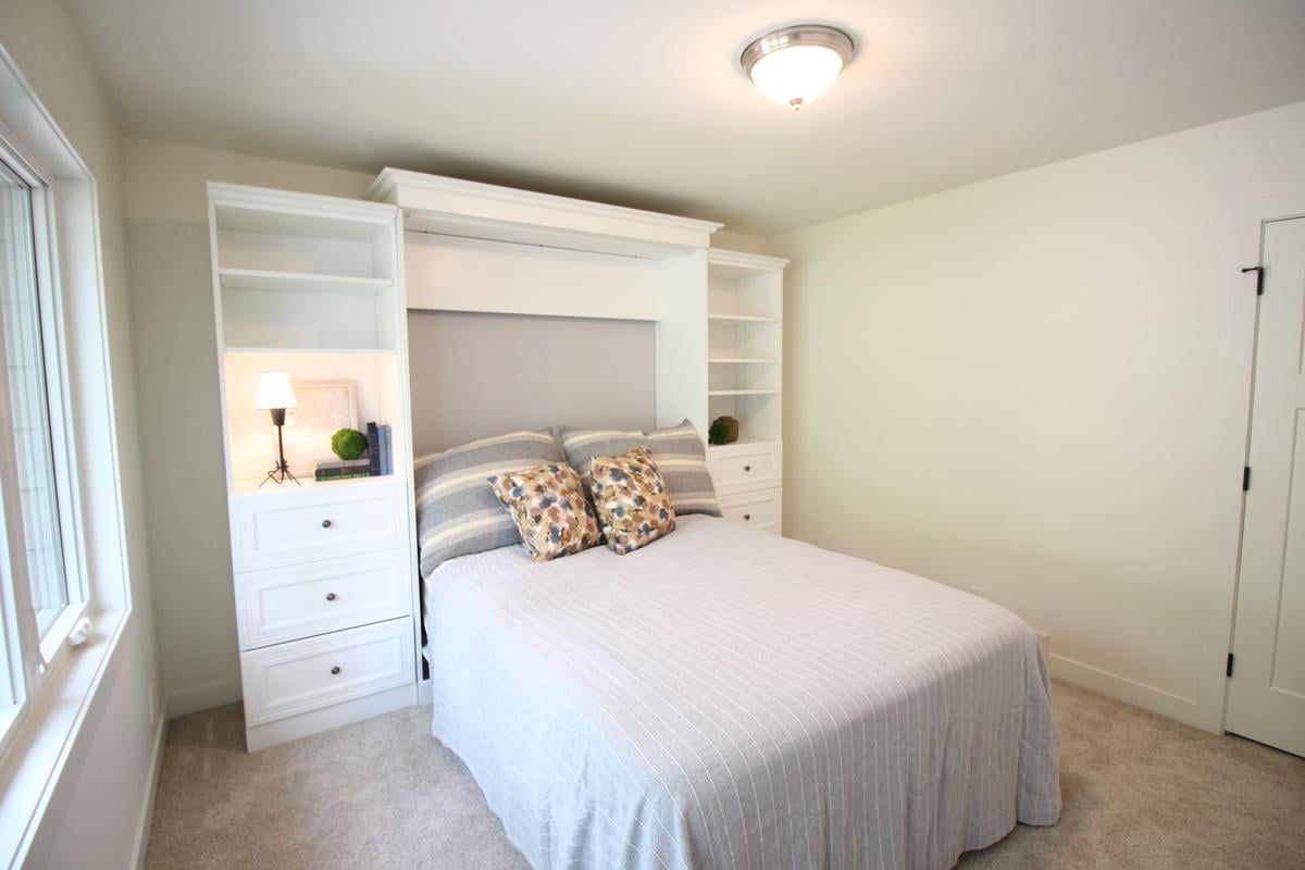 Functional custom guest bedroom with smart storage and white cabinetry by Ross Construction in Marathon, WI