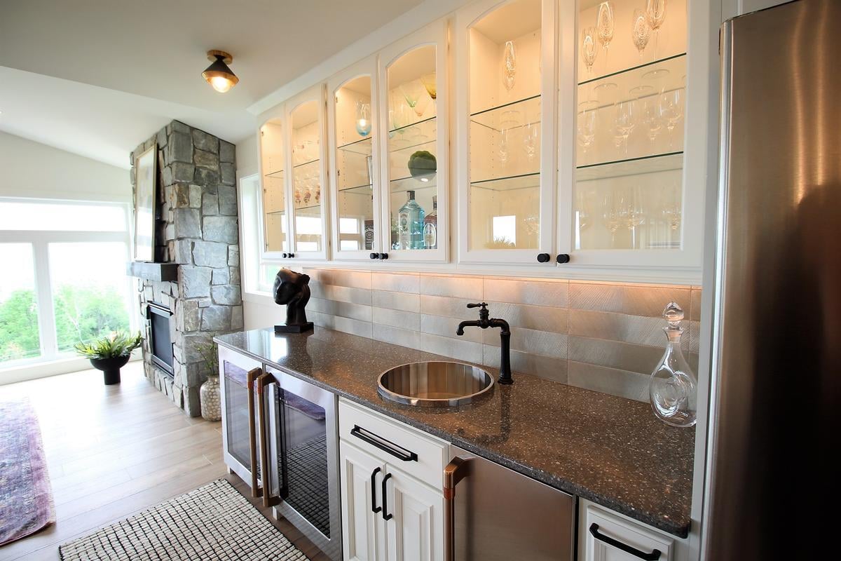 Light-filled wet bar area with stone fireplace in Ross Construction custom home in Rib Mountain, WI.