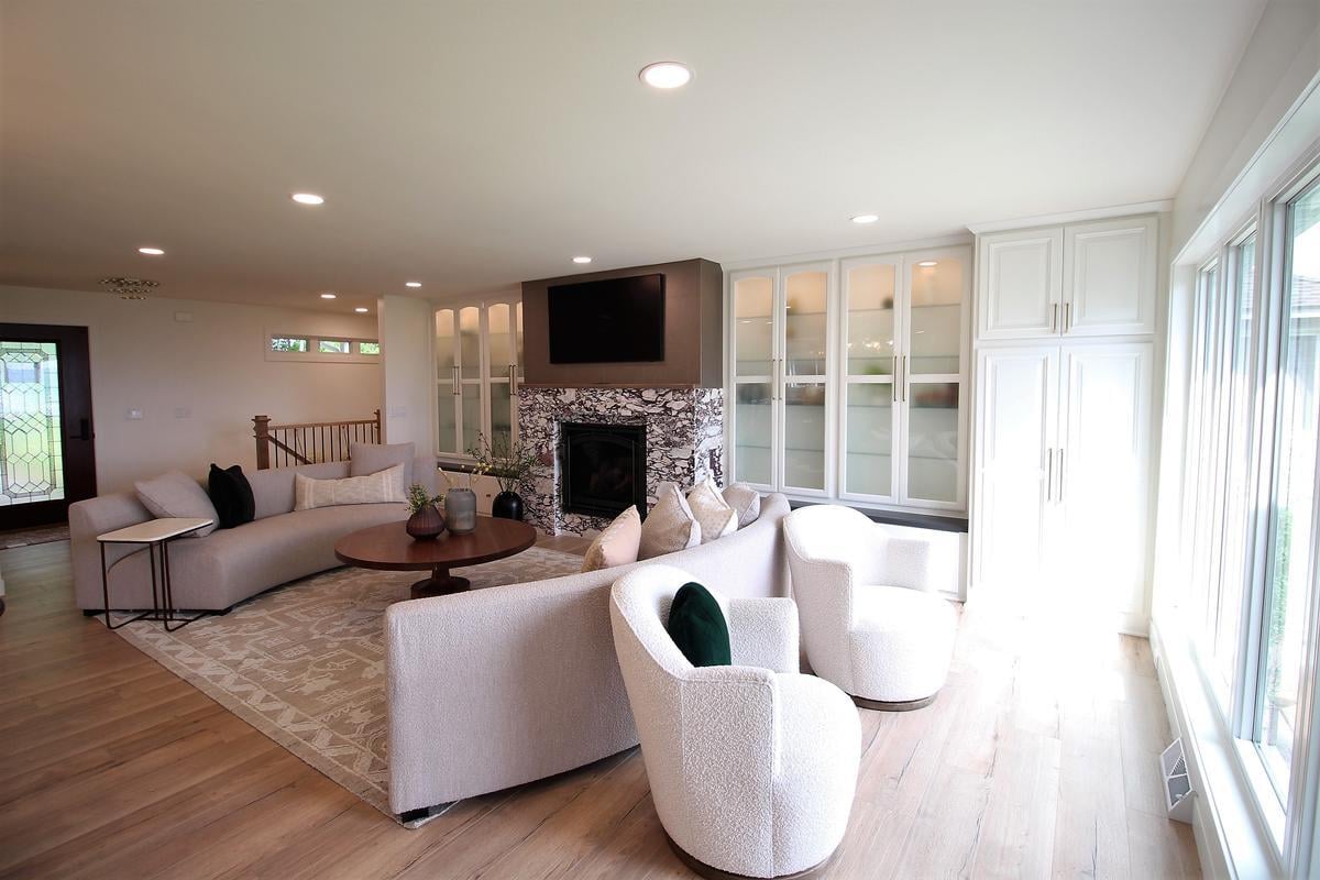 Natural light-filled lounge space with fireplace and plush seating in a custom home by Ross Construction in Wisconsin.