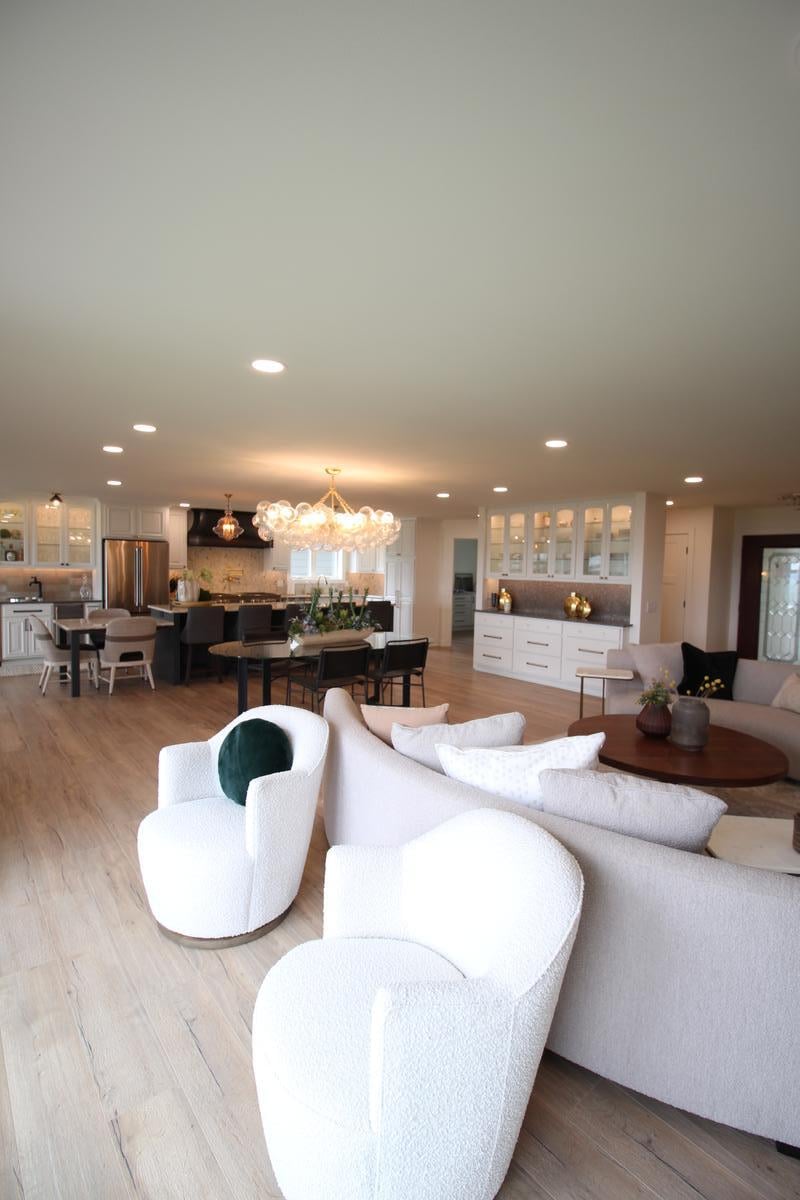Open concept living room with plush white seating and wood floors in custom home by Ross Construction in Marathon, WI