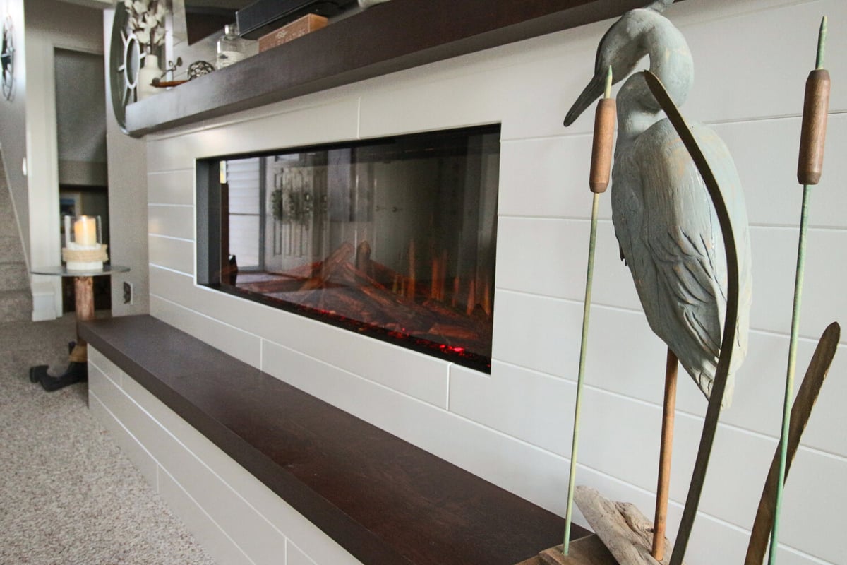 Custom fireplace with shiplap surround and wood mantel in Marathon home by Ross Construction.