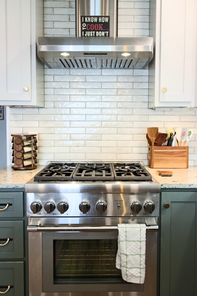 Marathon kitchen range wall featuring subway tile backsplash and stainless vent hood by Ross Construction.