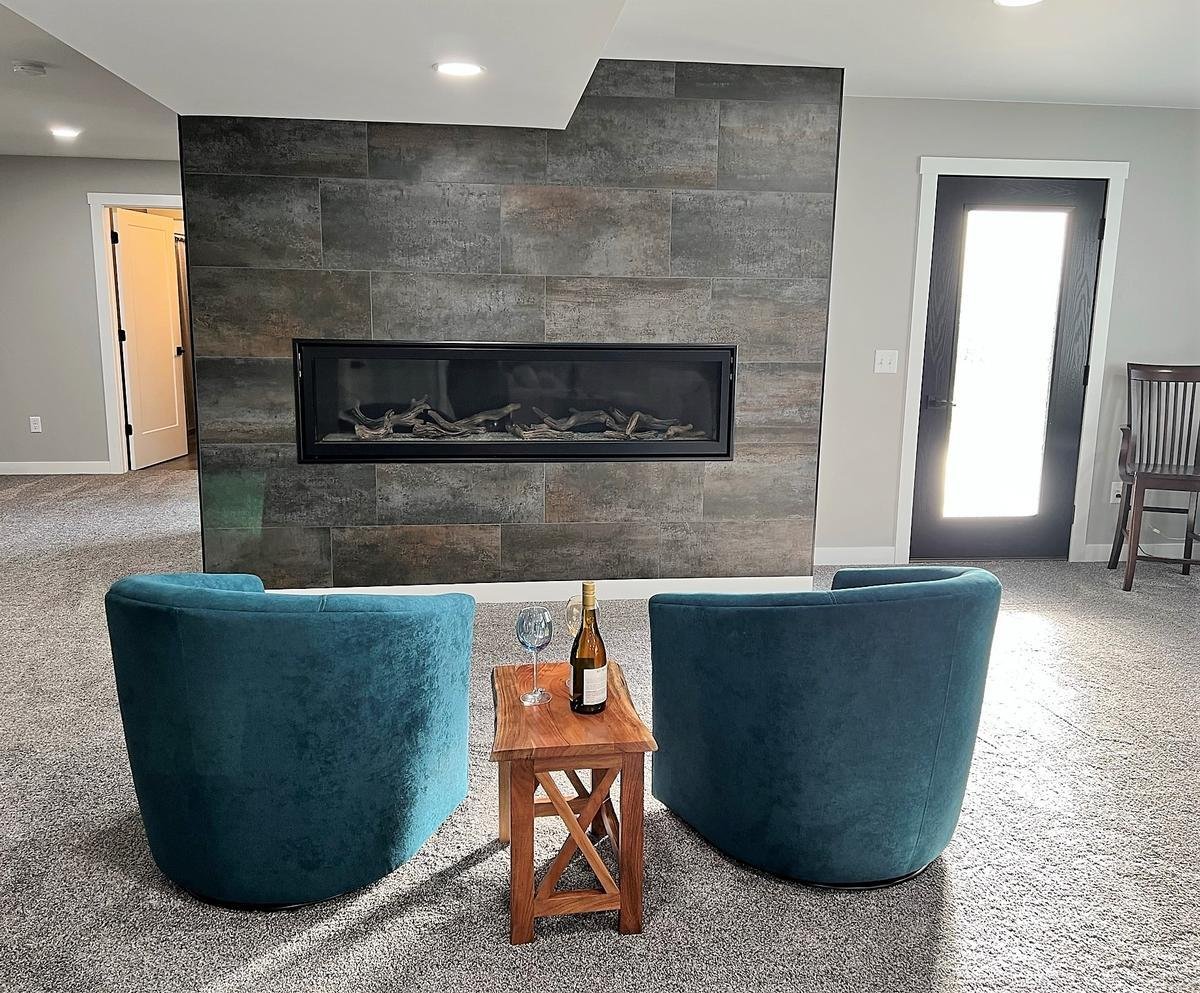 Basement lounge area with linear fireplace and cozy seating in Wausau home by Ross Construction.