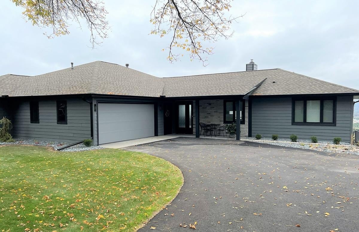 Exterior view of Lake Dubay custom home by Ross Construction with dark siding and stone accents.
