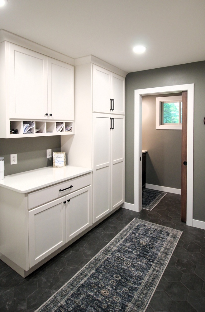Custom laundry room with white cabinetry and built-in desk area by Ross Construction in Marathon, WI.