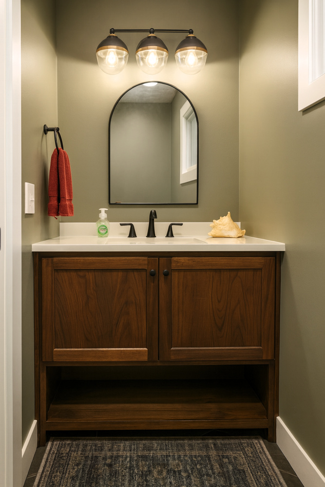 Narrow powder room with arched mirror and walnut vanity built in a Ross Construction custom home in Wausau, WI.