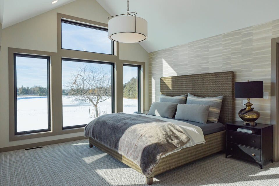 Bedroom with floor-to-ceiling windows and vaulted ceiling in Marathon, WI custom home by Ross Construction.
