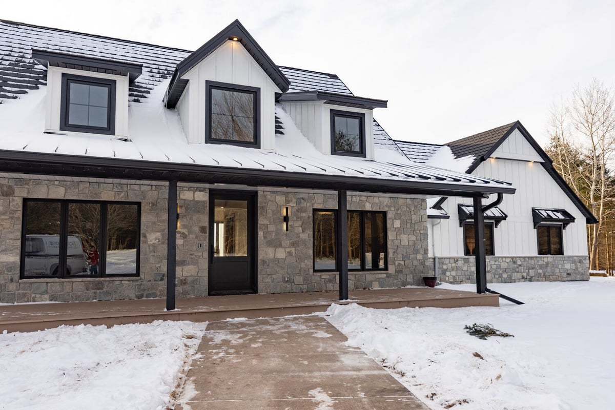Custom home exterior in winter by Ross Construction in Marathon, WI, featuring stone and board-and-batten siding.