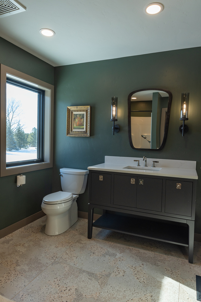 Dark green powder room with natural light and designer vanity in Marathon, WI home by Ross Construction.