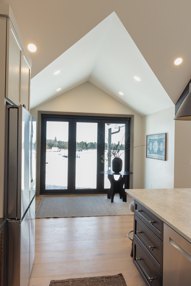 Light-filled kitchen nook with vaulted ceiling and black French doors in Wausau, WI custom home by Ross Construction.