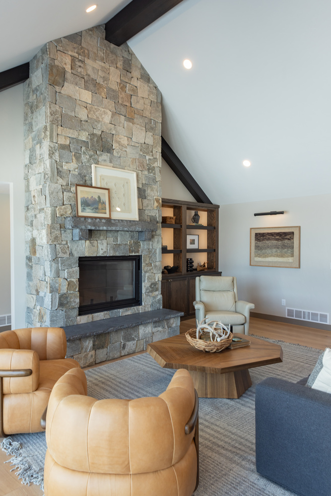 Living room with stone fireplace and leather seating in Ross Construction custom home in Wausau, WI.