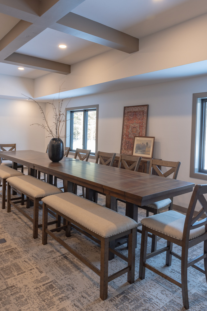 Spacious dining room in Marathon, WI custom home by Ross Construction with wood table and upholstered benches.