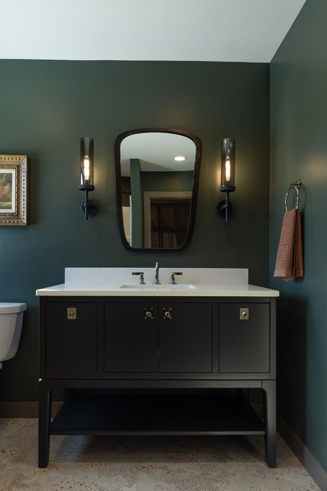 Stylish powder room with dark green walls and black vanity in custom home by Ross Construction in Wausau, WI.