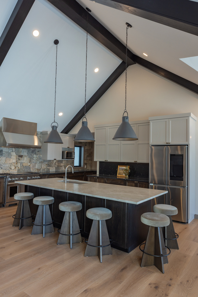 Vaulted ceiling kitchen by Ross Construction in Marathon, WI featuring large island and pendant lights.