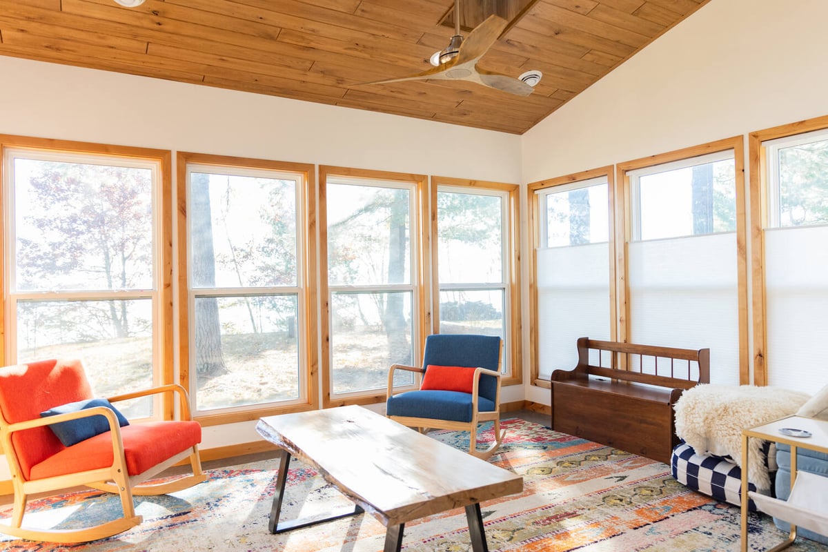 Bright sunroom with colorful chairs and wood ceiling by Ross Construction in Lake Dubay, WI.