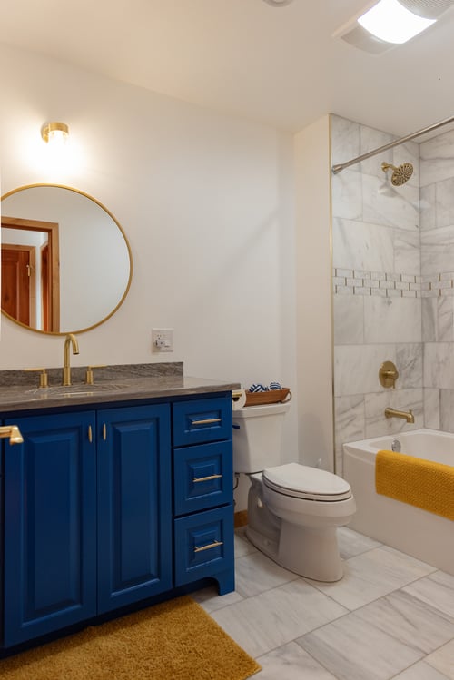 Custom bathroom with bright blue vanity and marble shower by Ross Construction in Marathon, WI.