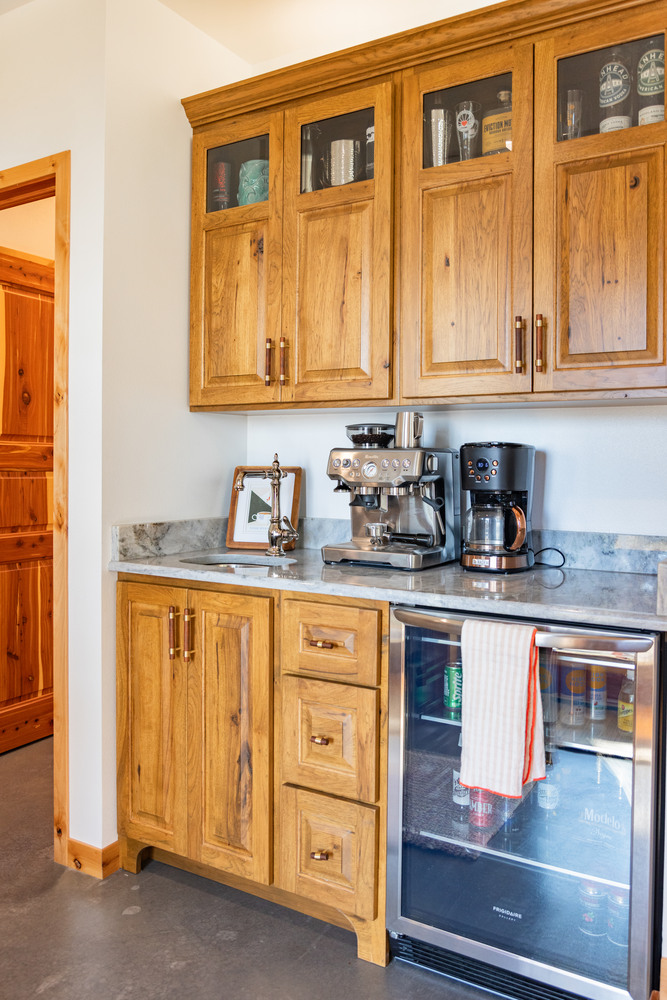 Custom home coffee bar with wood cabinetry and built-in beverage fridge by Ross Construction in Marathon, WI.