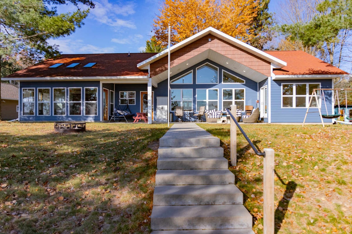 Full view of custom waterfront home by Ross Construction in Lake Dubay, WI with red shingle roof.