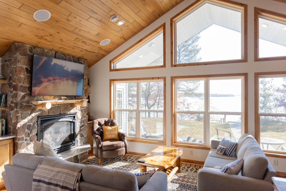 Living room with lake views, stone fireplace, and vaulted ceiling by Ross Construction in Lake Dubay, WI.