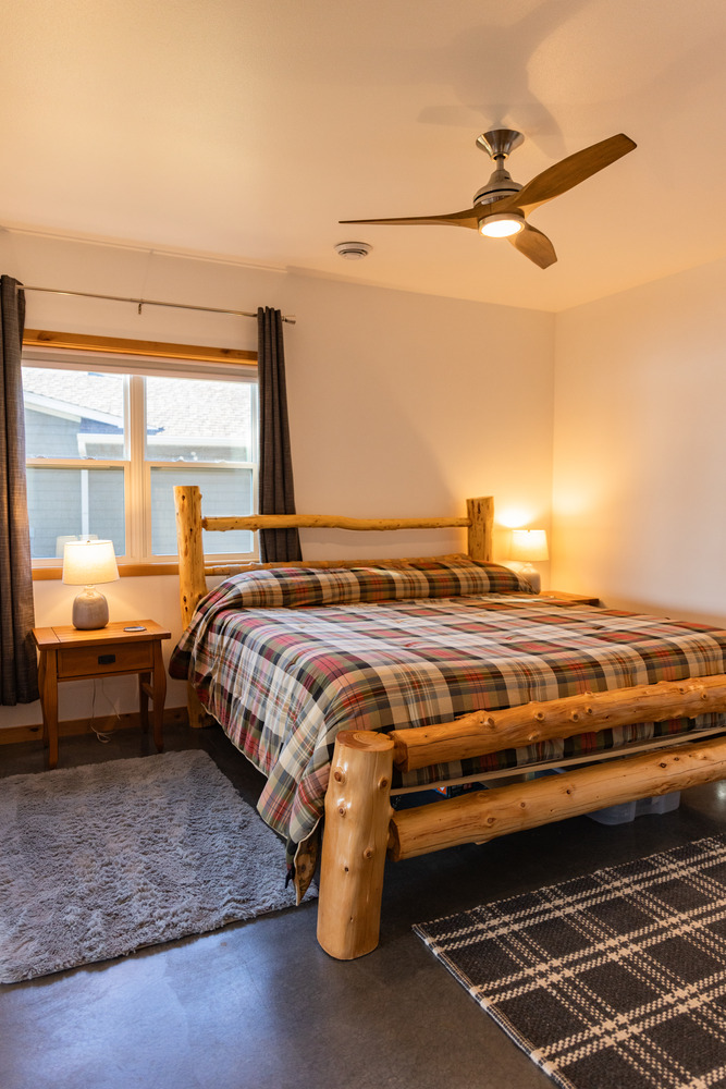 Rustic bedroom with log-frame bed and plaid bedding by Ross Construction in Marathon, WI.