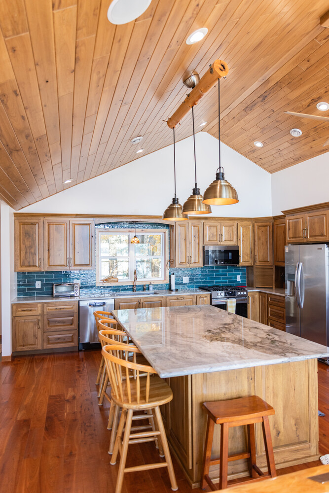 Wide view of wood-accented kitchen with teal tile backsplash in Marathon, WI custom home by Ross Construction.