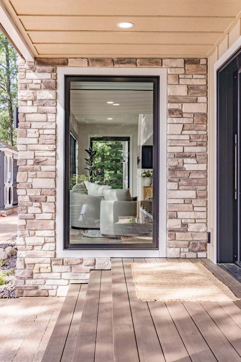 whole home remodel exterior covered porch with stone columns and sliding door minocqua wi