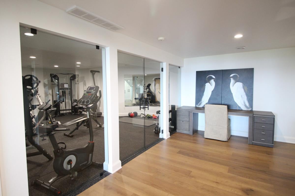 Basement fitness room with cardio equipment and stylish home office by Ross Construction in Rib Mountain, WI