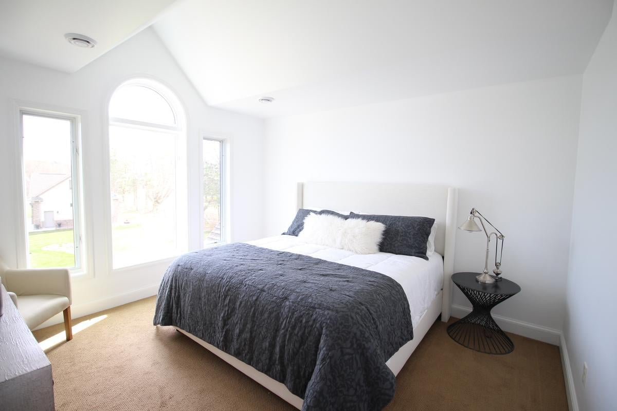 Bright modern bedroom with vaulted ceilings in custom home by Ross Construction in Marathon, WI.