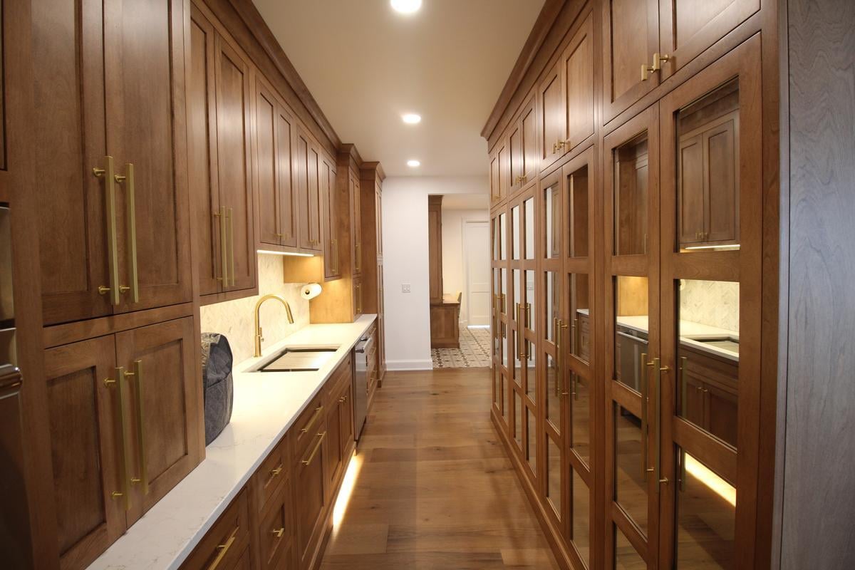 Custom home galley kitchen with full-height wood cabinetry and brass fixtures by Ross Construction in Wausau, WI