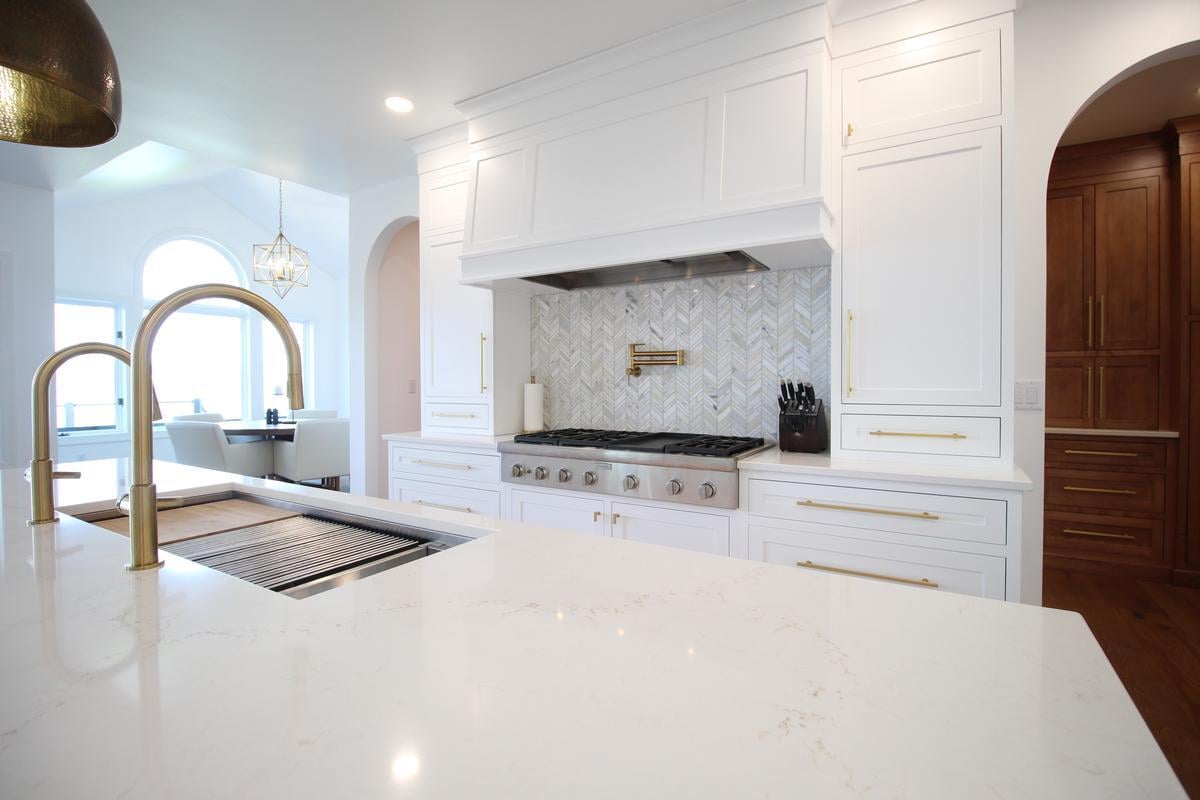 Designer kitchen with white cabinetry and quartz countertops in Ross Construction custom home in Lake Dubay, WI.