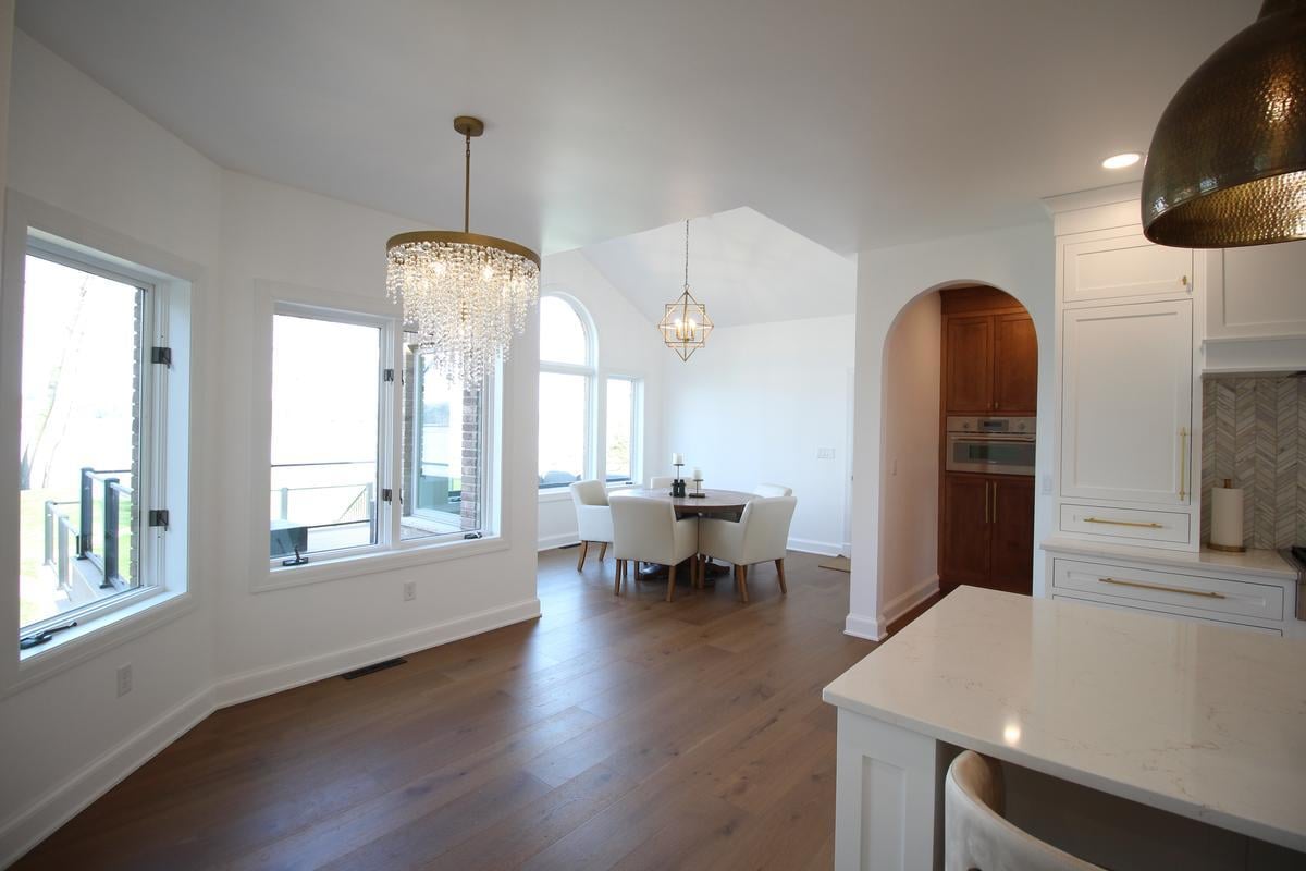 Dining area with arched windows and round table in Ross Construction custom home in Lake Dubay, WI.