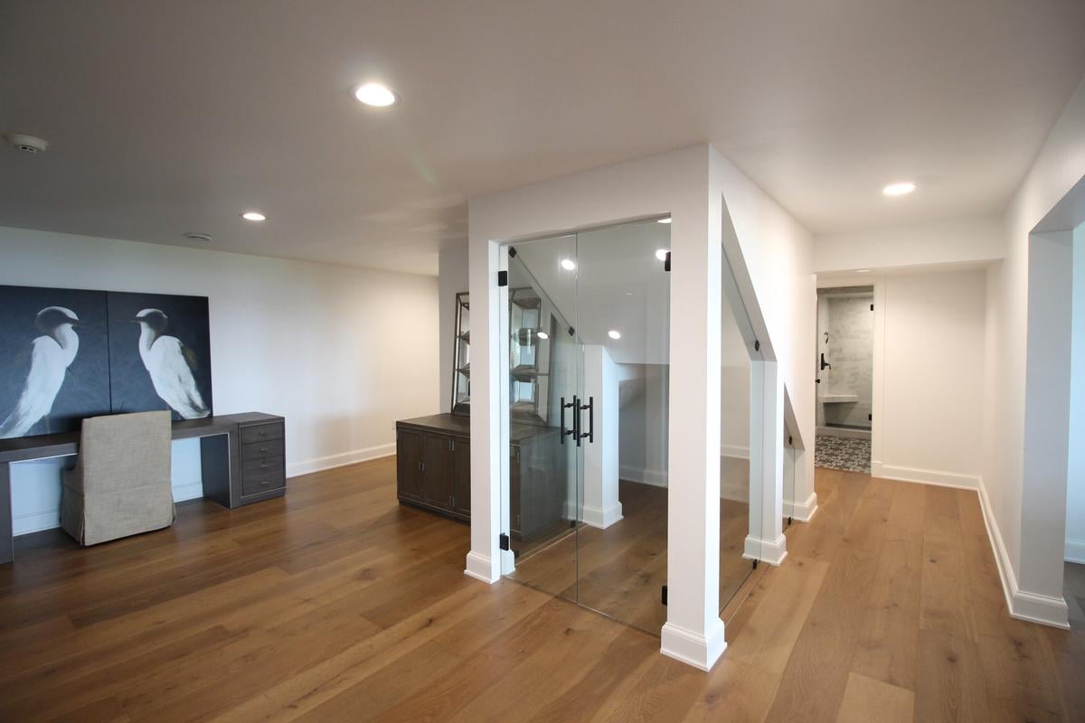 Office nook with custom desk and glass-enclosed staircase in a Ross Construction home in Lake Dubay, WI