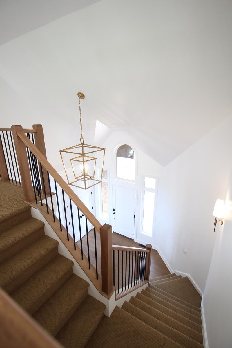 Open staircase with wood handrails and white walls in custom home by Ross Construction in Edgar, WI.