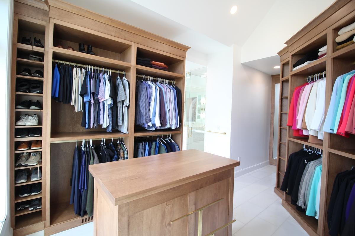 Organized walk-in closet with mens clothing and shoe shelves by Ross Construction in Rib Mountain, WI