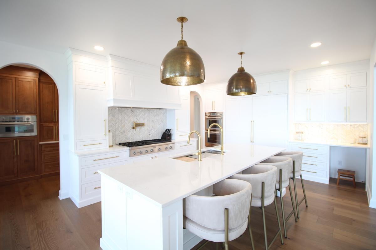 White kitchen with brass hardware and dual pendant lights by Ross Construction in Lake Dubay, WI.