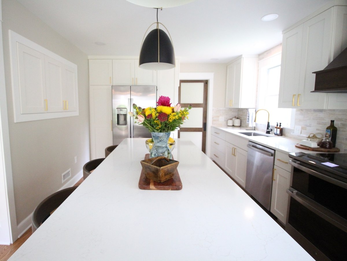Bright custom kitchen with white cabinetry and black pendant lighting by Ross Construction in Rib Mountain, WI.
