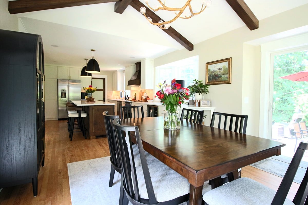 Bright kitchen and dining area with modern chandelier and black chairs by Ross Construction in Rib Mountain, WI.