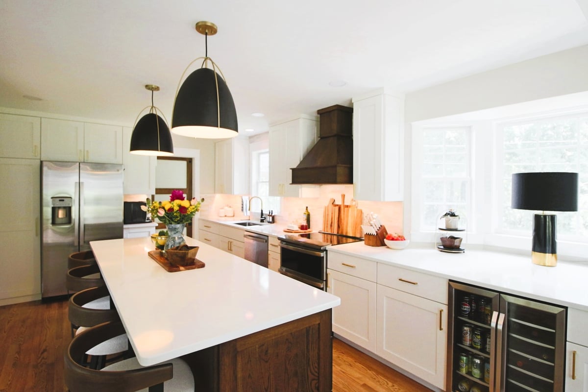 Bright kitchen with large island and dark wood range hood in custom home by Ross Construction in Rib Mountain, WI.