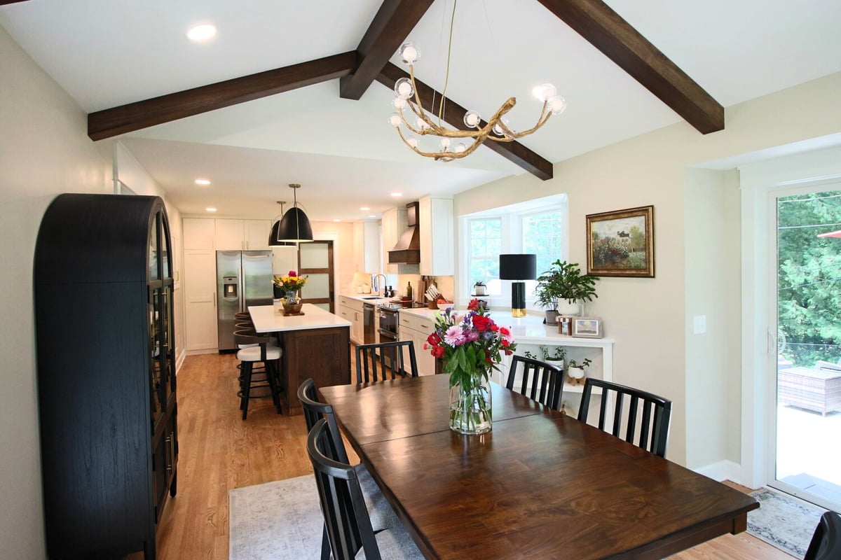 Dining room and kitchen view with exposed ceiling beams in Ross Construction custom home in Marathon, WI.