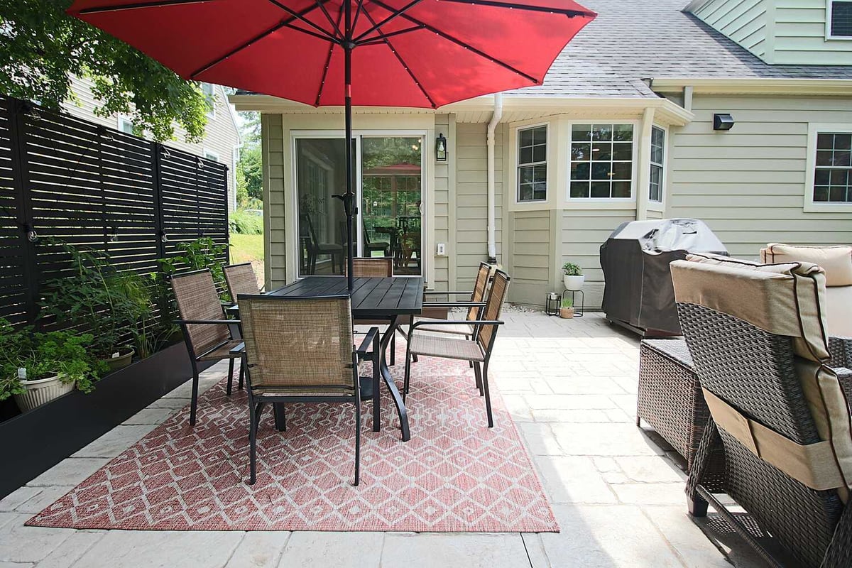 Outdoor patio with red umbrella and dining furniture in Ross Construction custom home in Lake Dubay, WI.