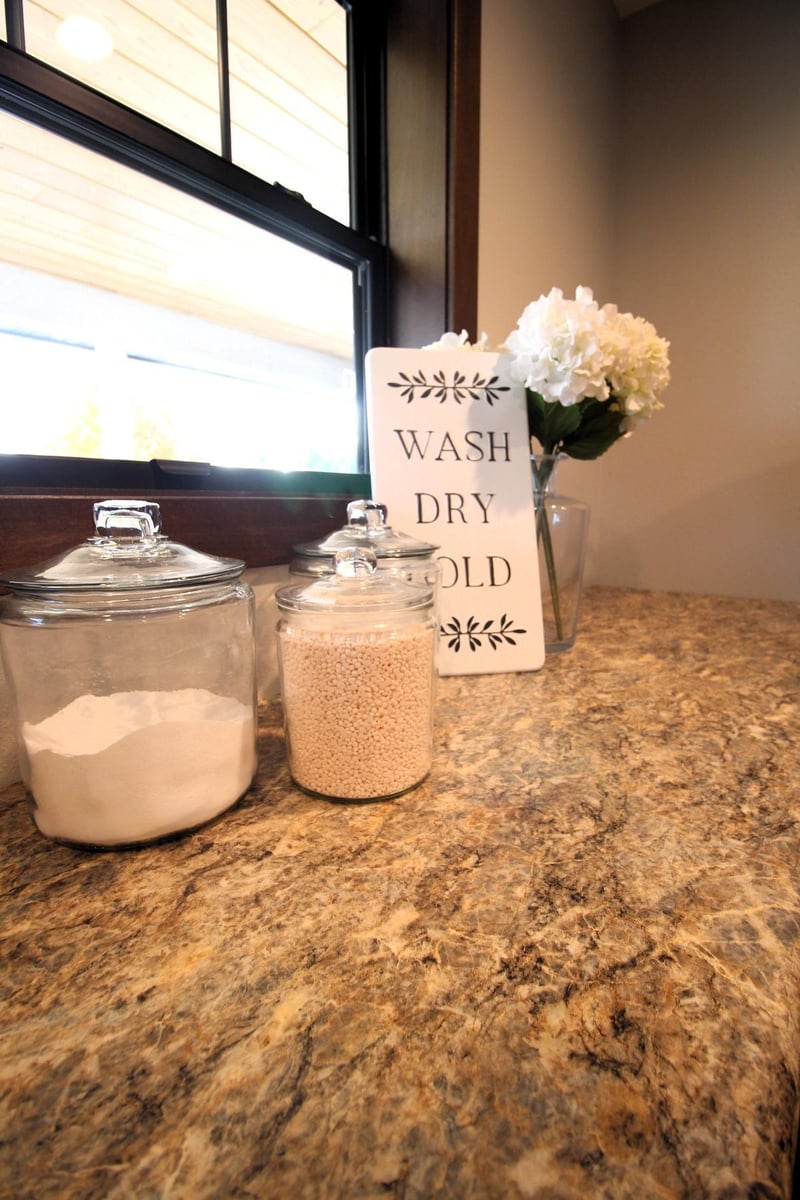 Laundry countertop vignette in Marathon, WI custom home by Ross Construction with jars and decor sign.
