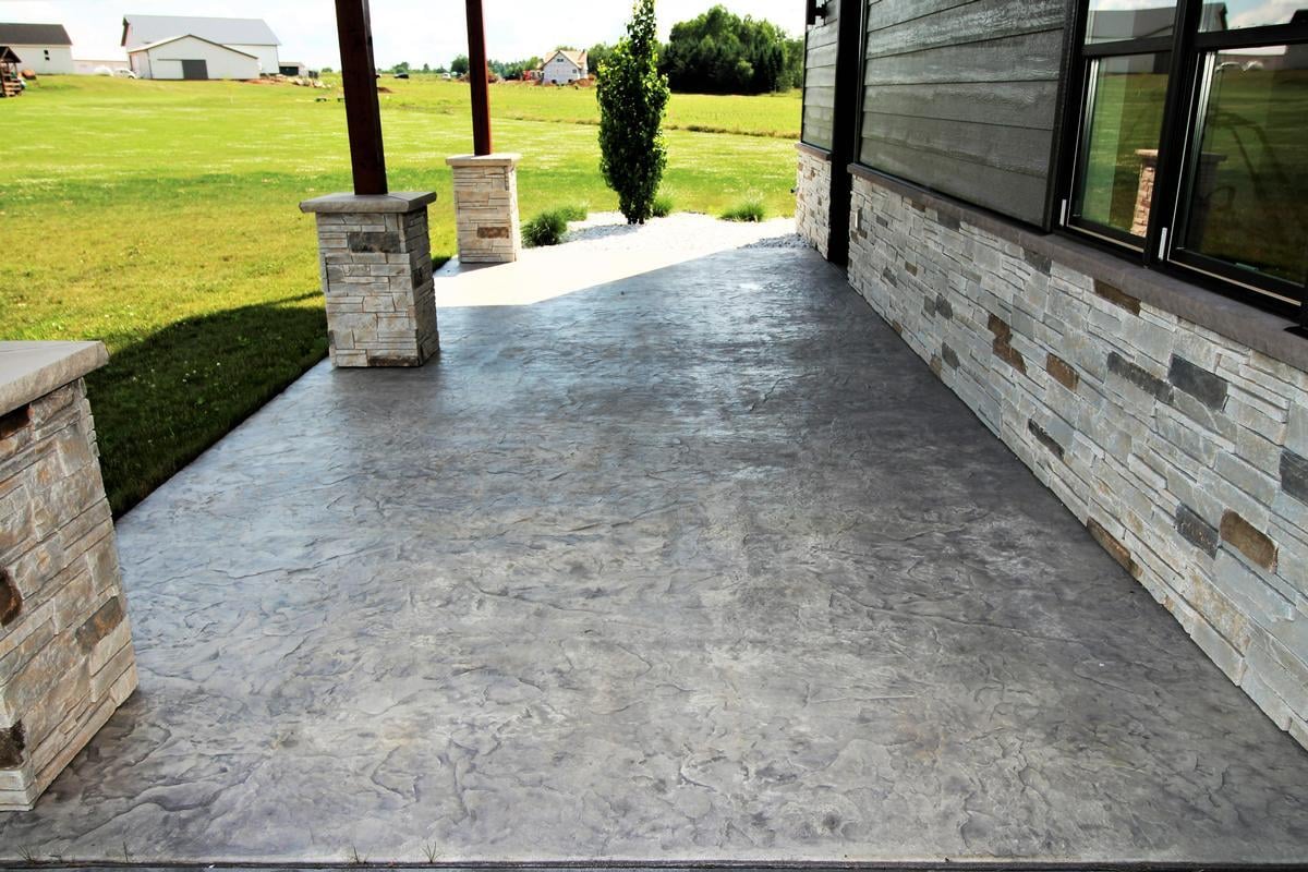 Back patio view of custom home in Edgar, WI by Ross Construction with stone pillars and stamped concrete.