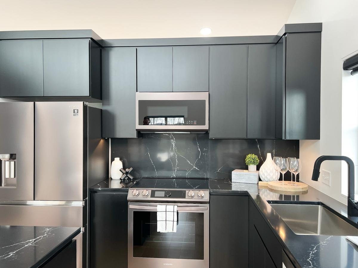 Black modern kitchen cabinetry with stainless steel appliances in custom Wisconsin home by Ross Construction.