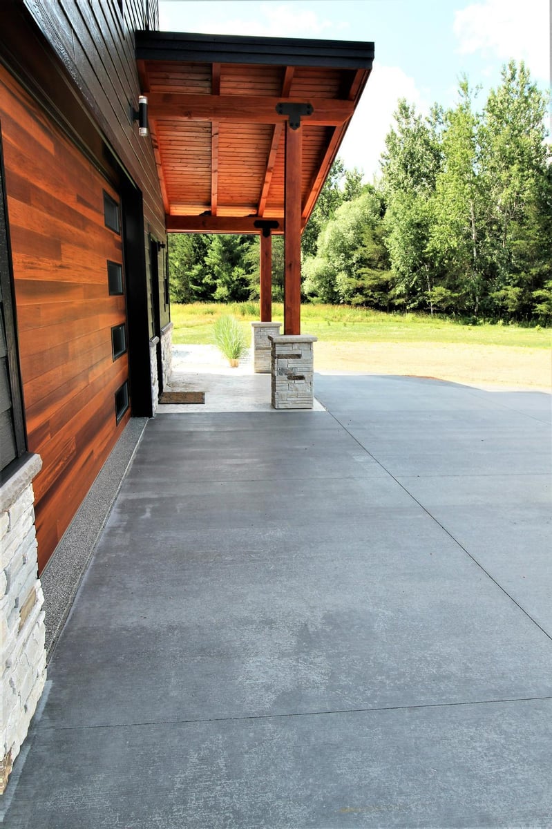 Lake Dubay, WI home exterior by Ross Construction showcasing concrete drive and natural wood finishes.