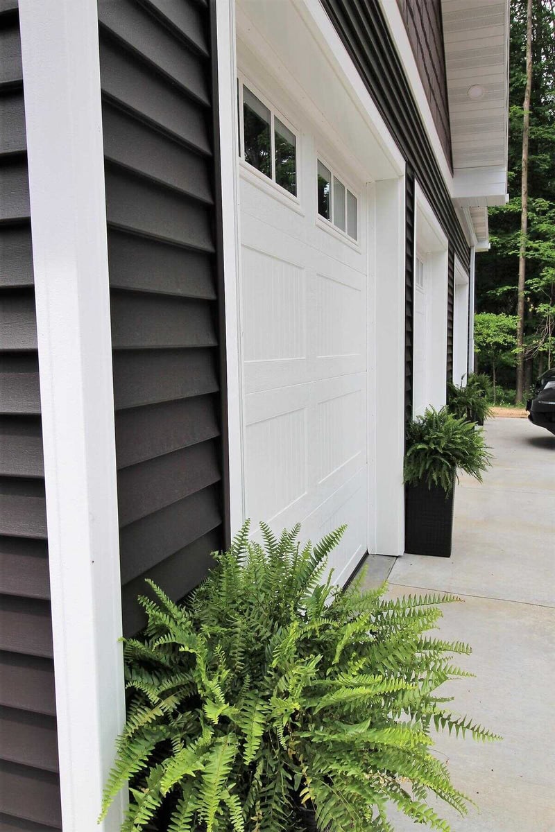 Close-up of garage exterior with white doors and black siding in a Ross Construction custom home in Marathon, WI.