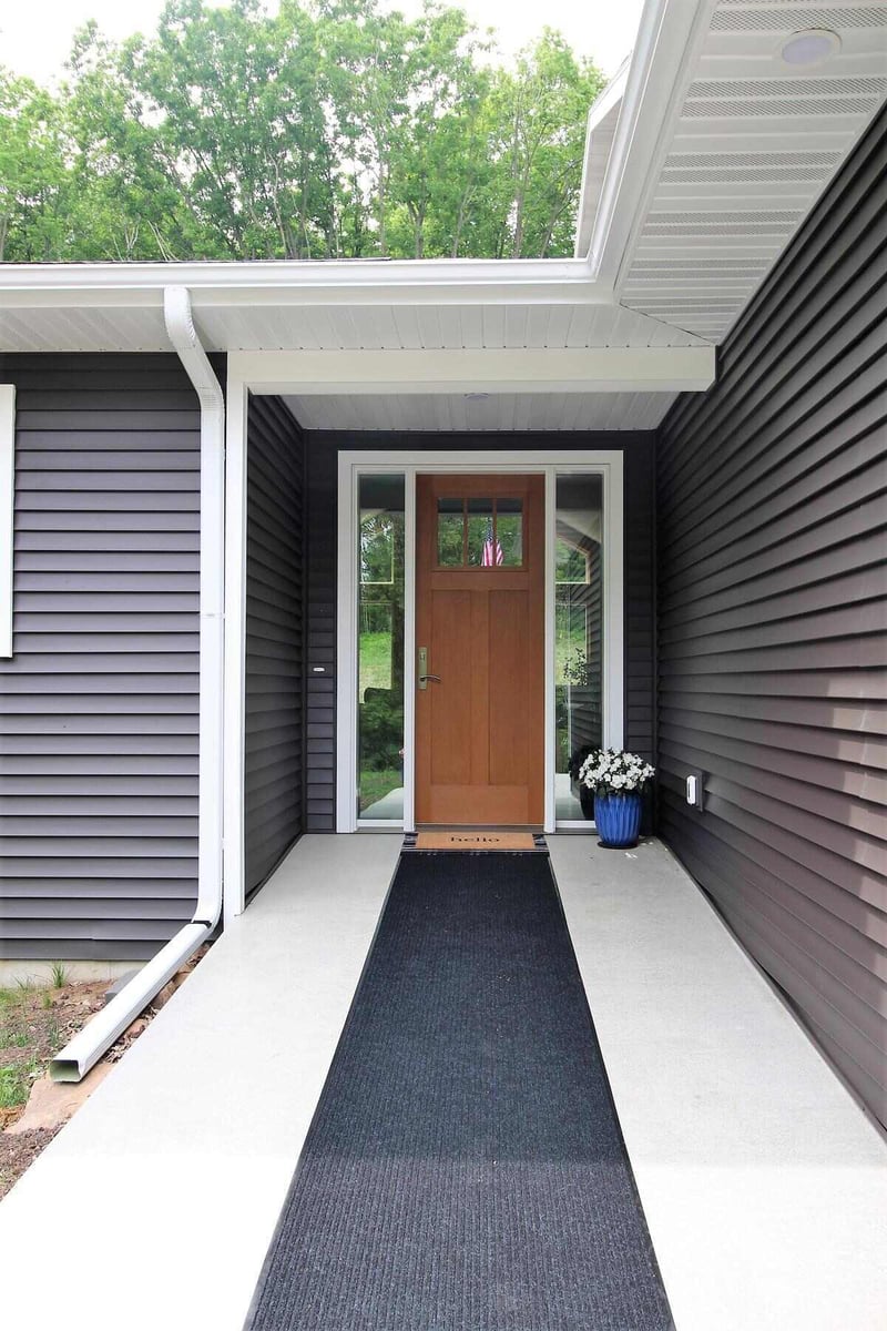 Front entry with wood door and dark siding in a custom home by Ross Construction in Lake Dubay, WI.