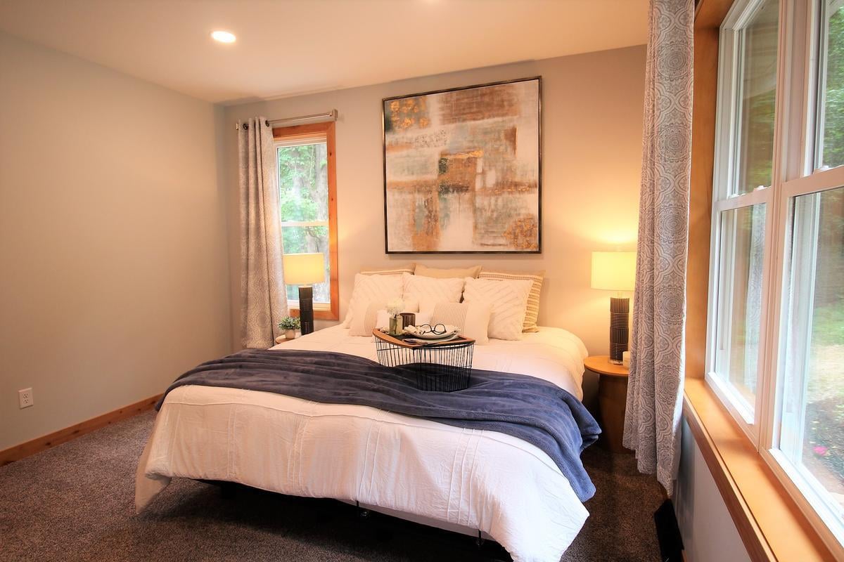 Guest bedroom with large window and neutral décor in a Ross Construction custom home in Lake Dubay, WI.